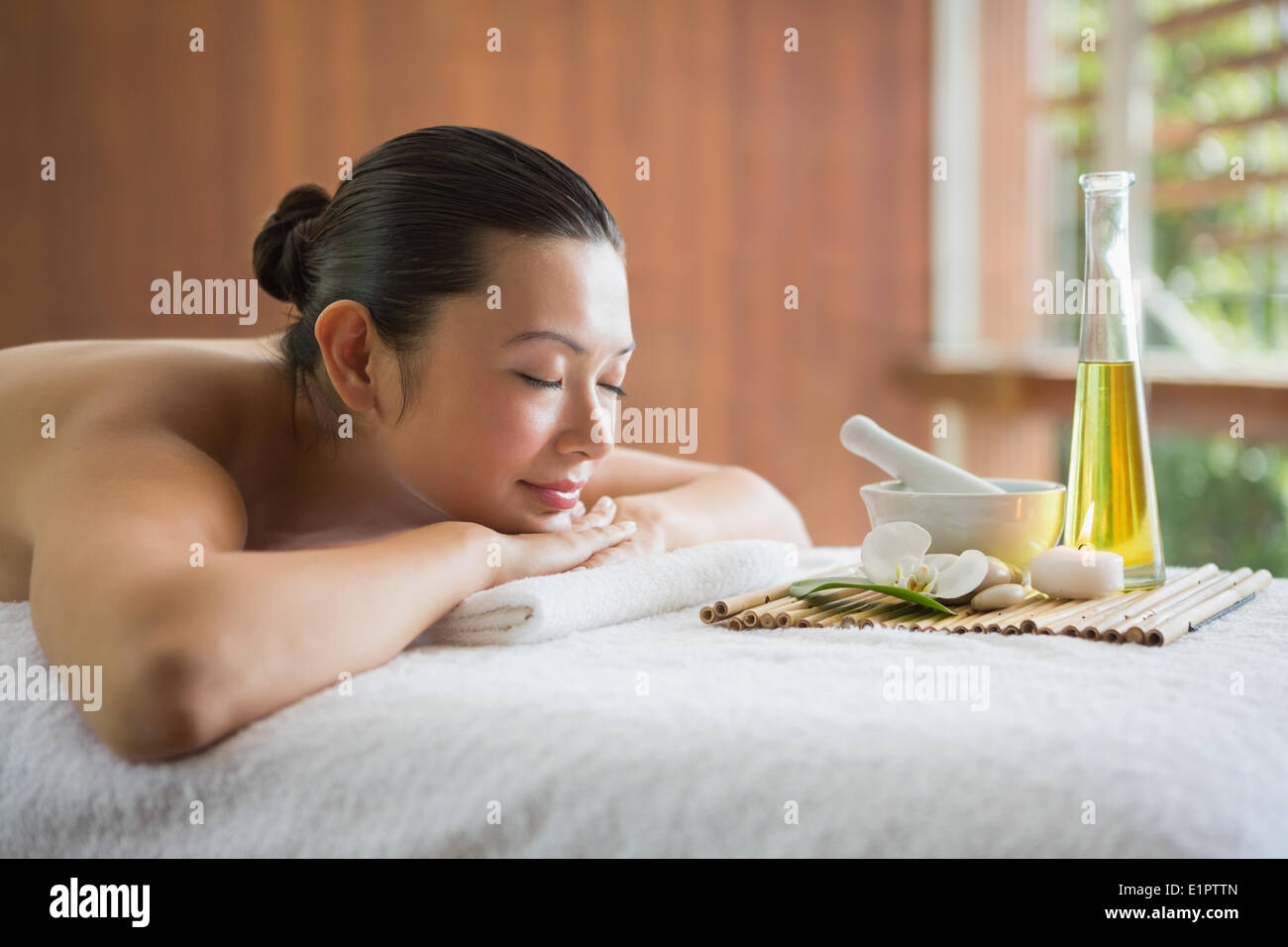Brünette auf Massagetisch liegend mit Tablett mit Beauty-Behandlungen Stockfoto