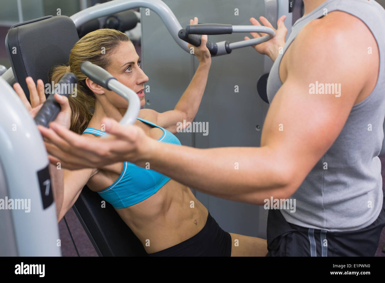Persönlicher Trainer coaching weibliche Bodybuilder mit Gerät für Krafttraining Stockfoto