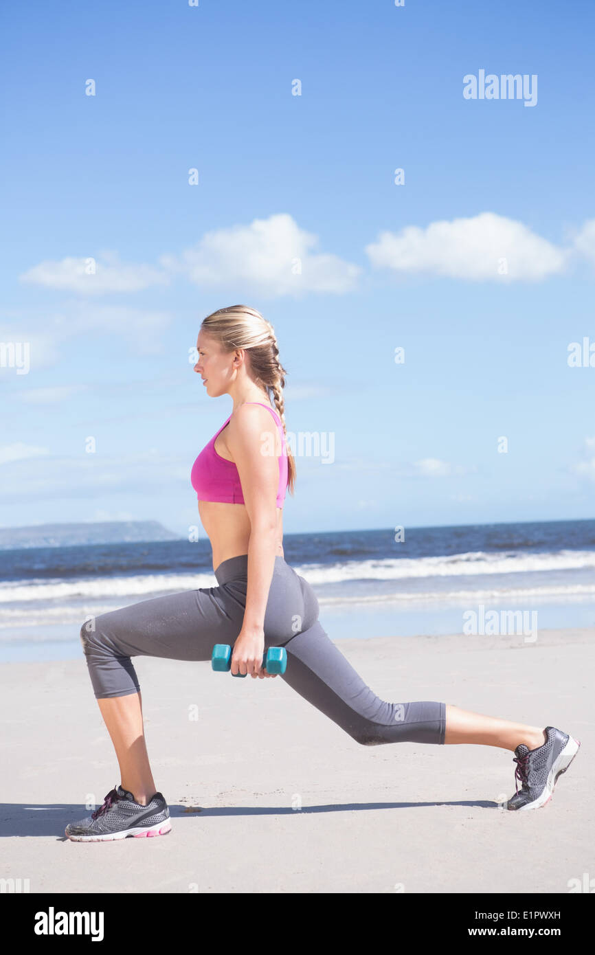Fit Woman Workout mit Hanteln auf dem Strand Longieren Stockfoto