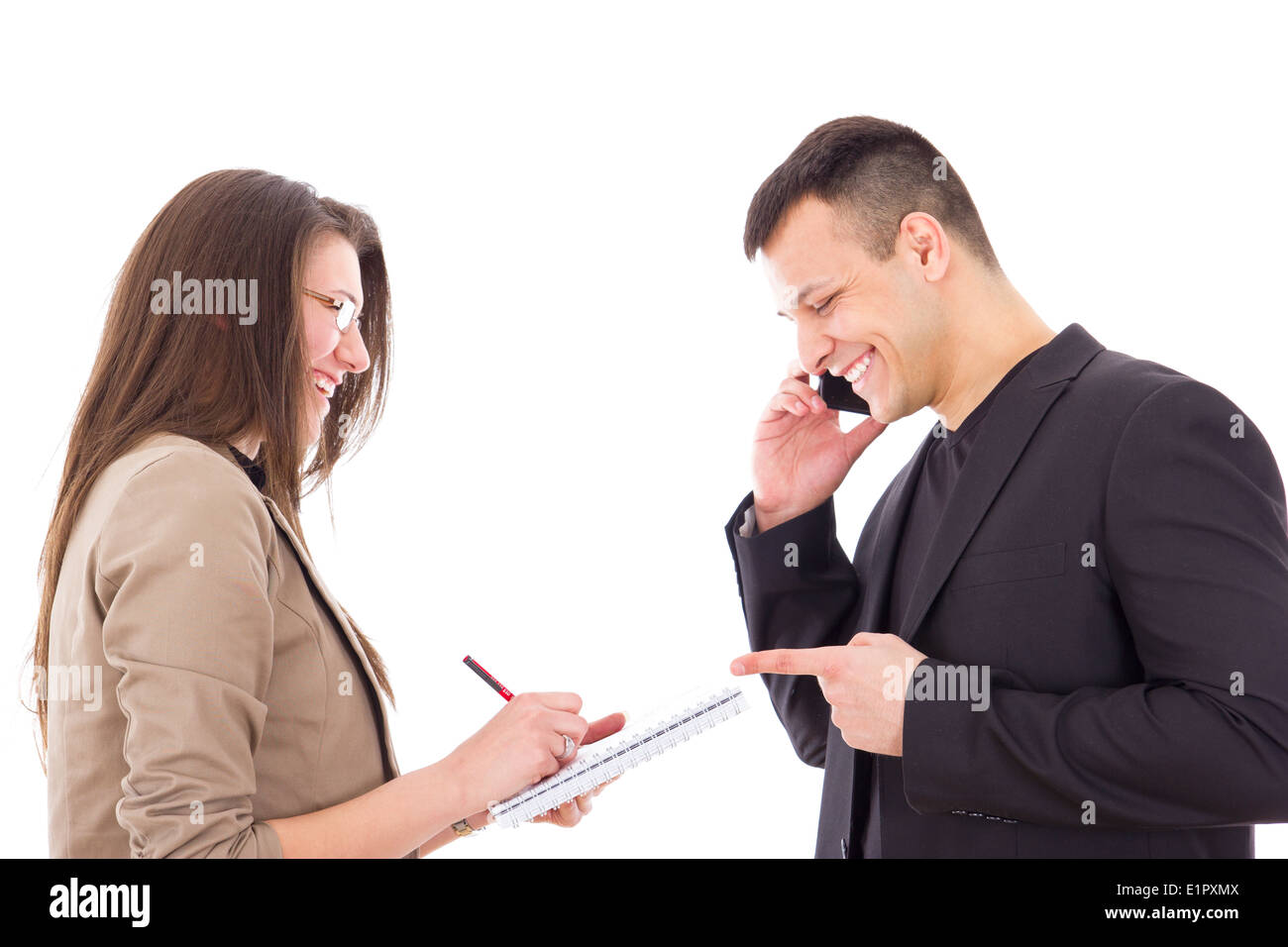 zufriedener und glücklicher Geschäftsmann auf das Telefon und seine Sekretärin Notizen aufschreiben Stockfoto