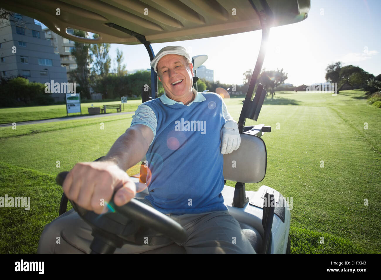 Golfer seinem Golfbuggy fahren und lächelt in die Kamera Stockfoto