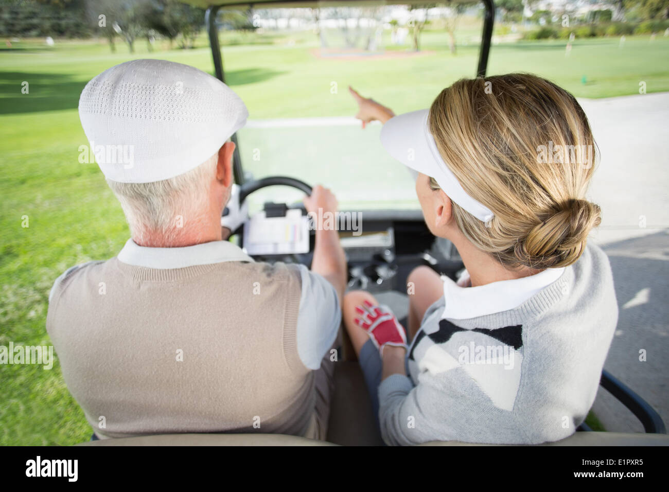 Golf paar mit Frau zeigt in ihrem Golfbuggy fahren Stockfoto