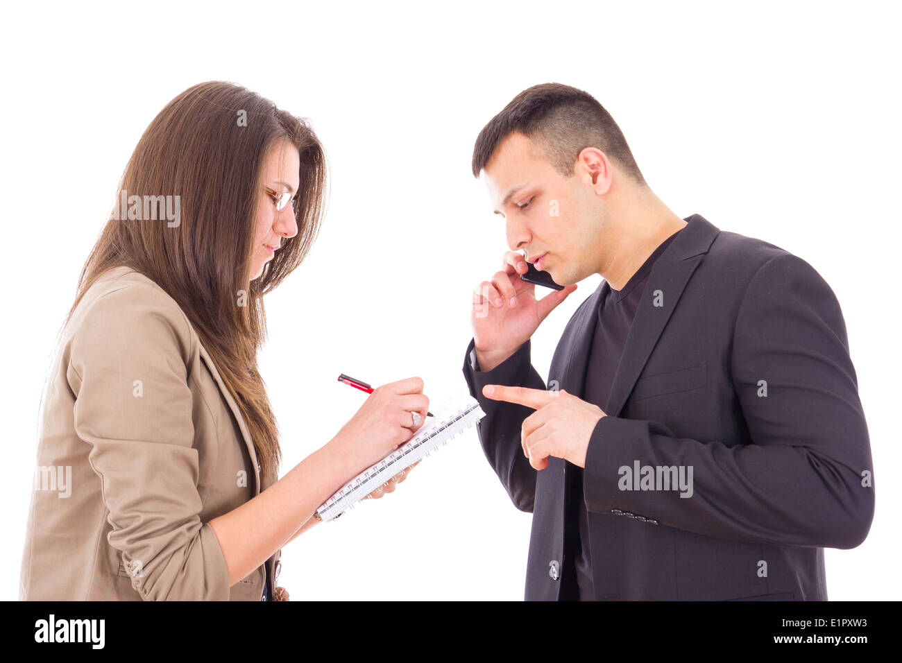ernsthaften Geschäftsmann auf das Telefon und seine Sekretärin Notizen aufschreiben Stockfoto