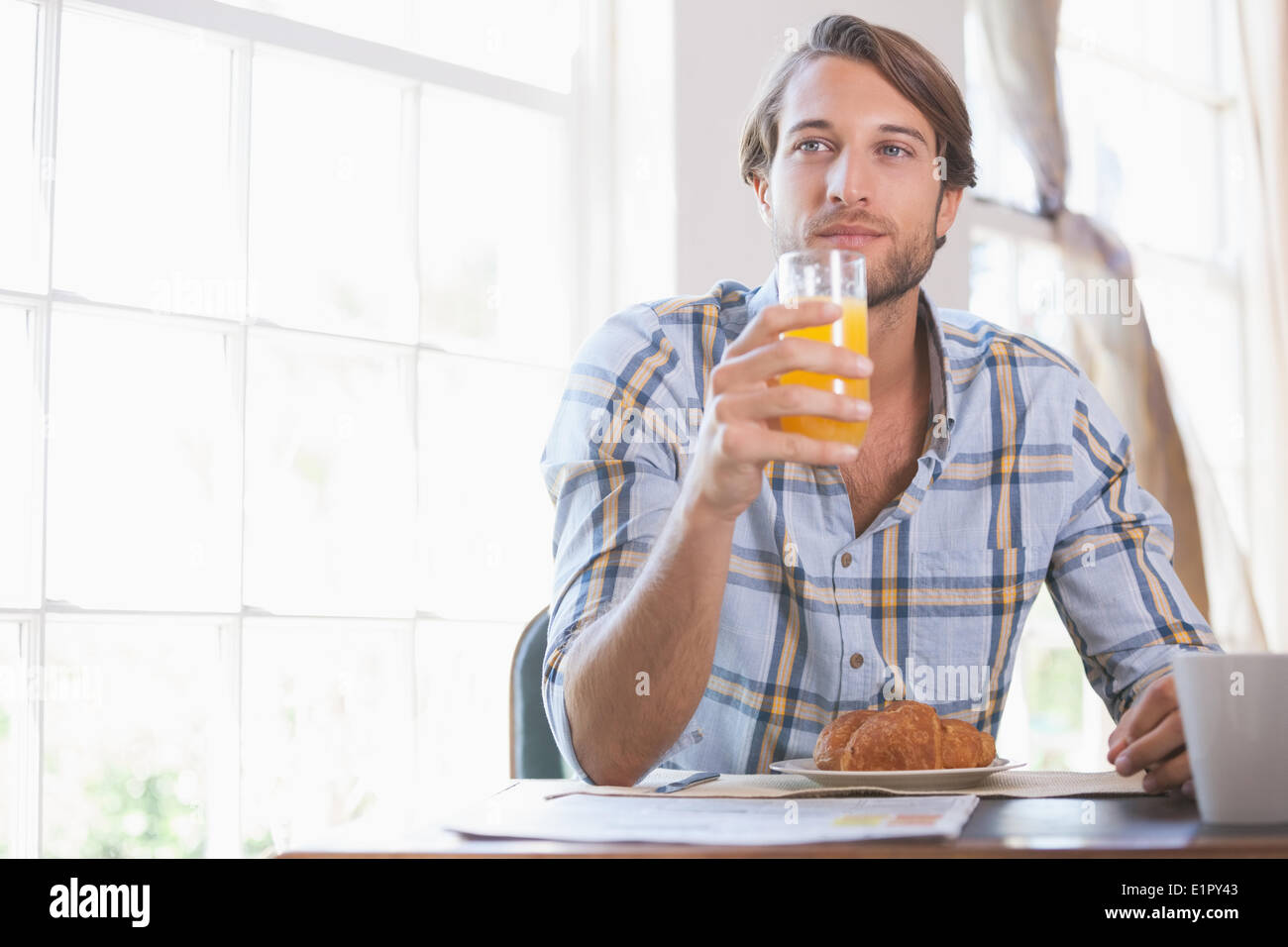 Gut aussehender Mann trinken Orangensaft beim Frühstück Stockfoto