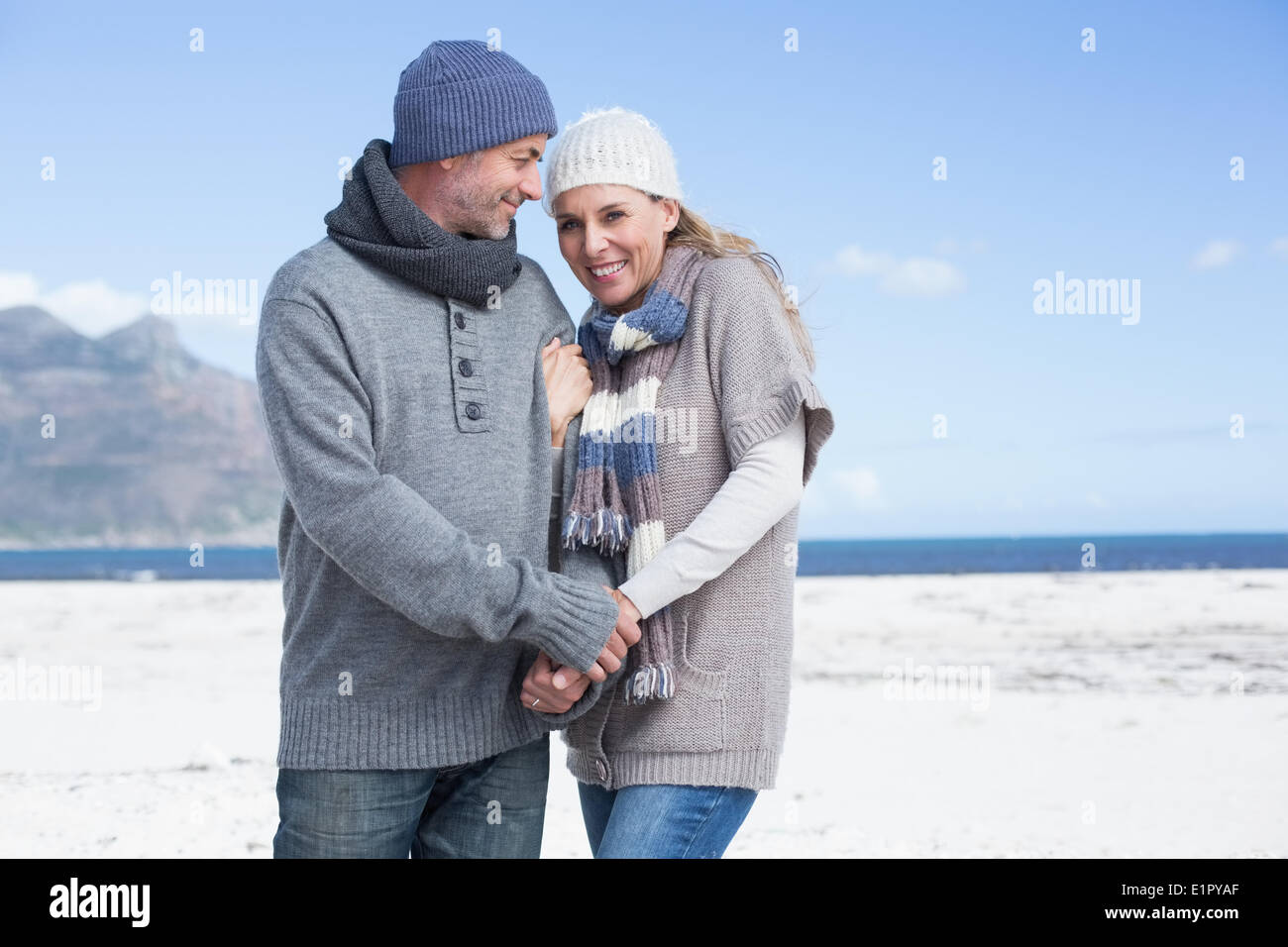 Lächelnde paar stehen am Strand in warme Kleidung Stockfoto