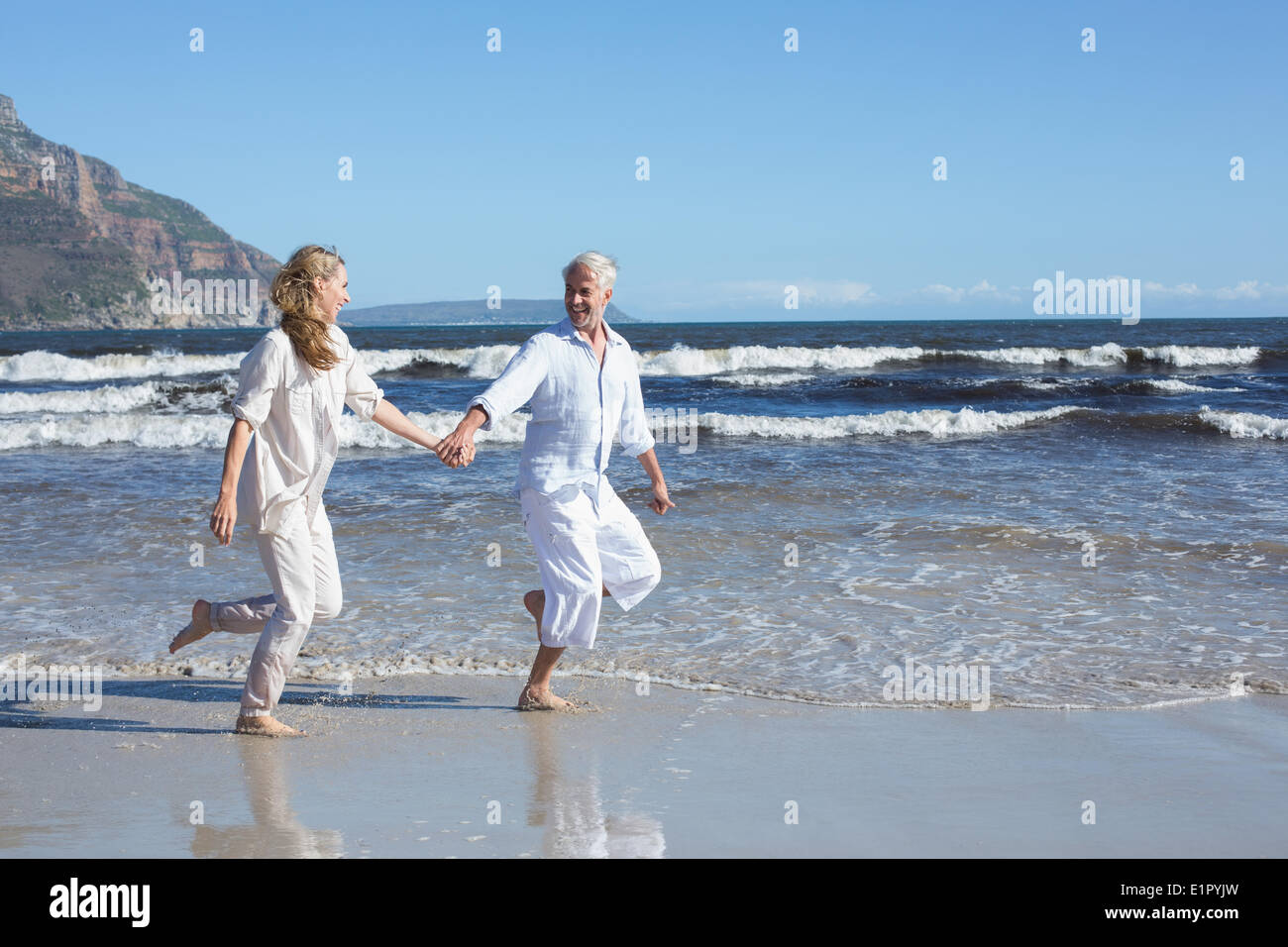 Glückliches Paar überspringen barfuß am Strand Stockfoto