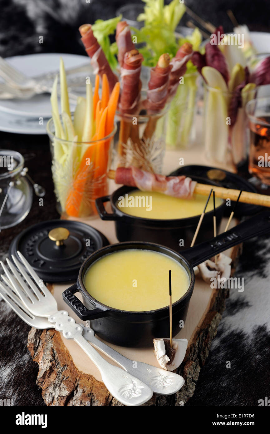 Einzelnen Käsefondue mit Brot-Sticks umhüllt von Parmaschinken und rohes Gemüse Stockfoto