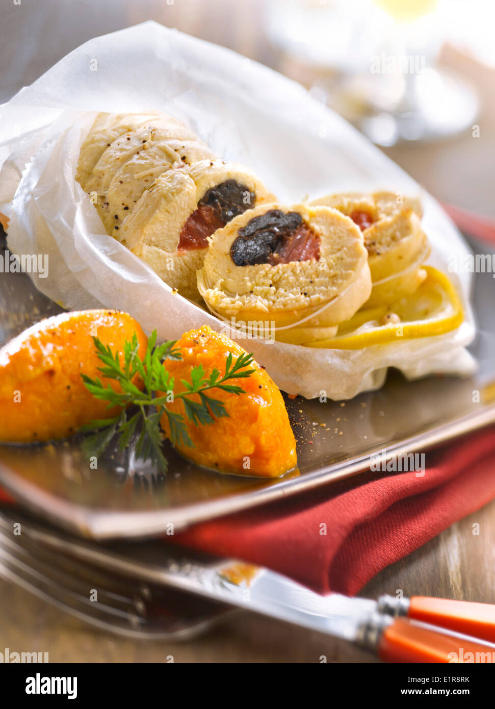 Huhn mit Zitrusfrüchten und Pflaumen gekocht in Wachspapier, Karottenpüree Stockfoto