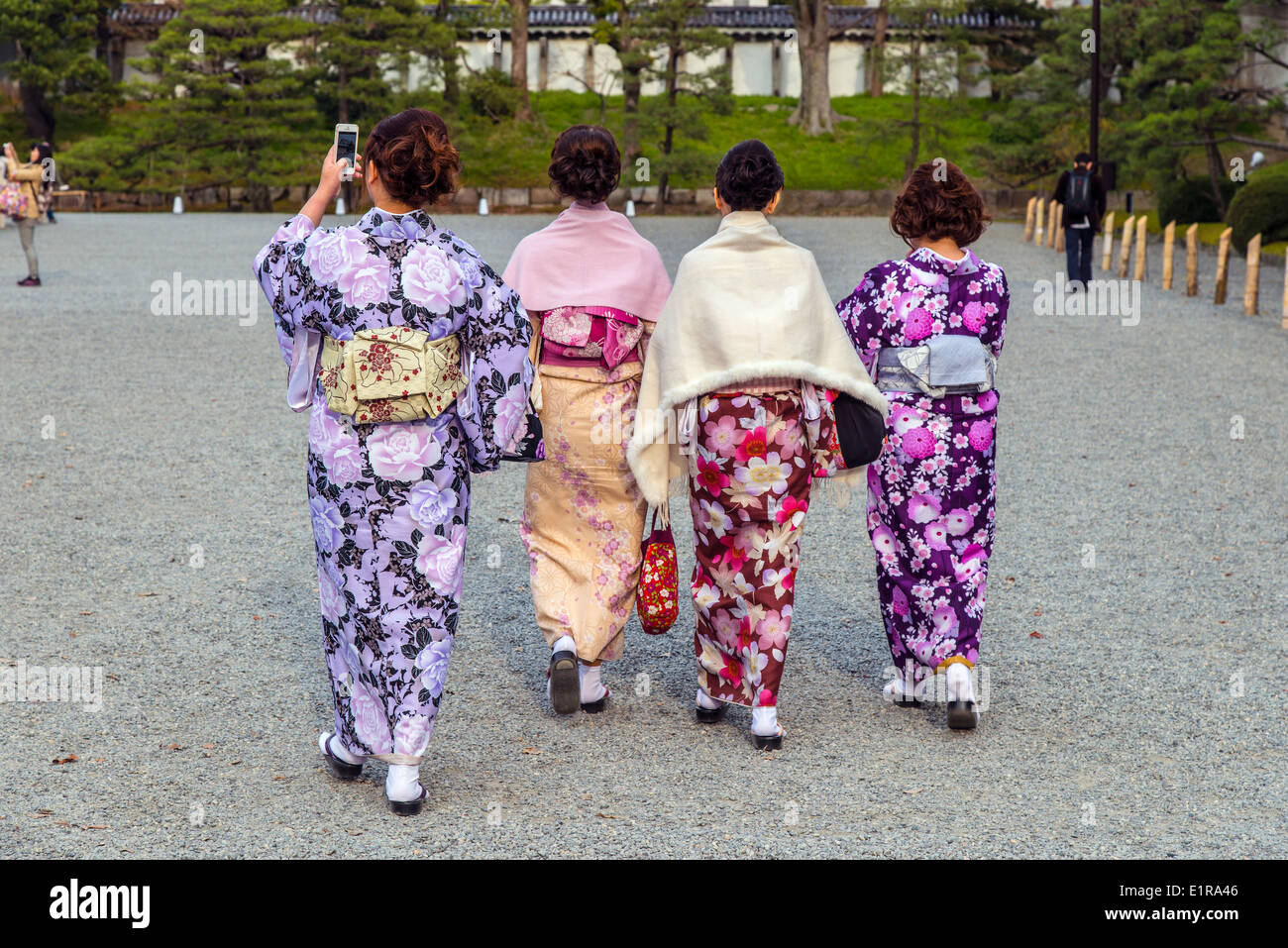 Vier japanische Frauen in traditioneller Tracht, die zu Fuß in Kyoto Imperial Park, Kyoto, Japan Stockfoto