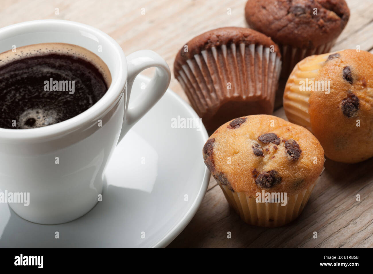 Muffins mit Schokoladenstückchen und Tasse Kaffee auf Holztisch Stockfoto