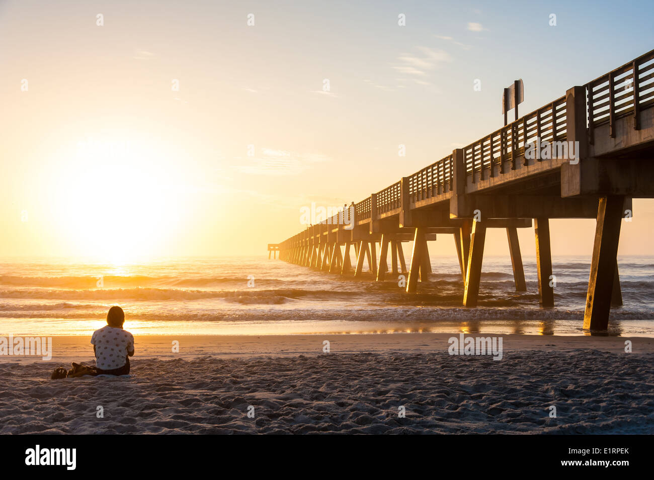 Junge Frau im Hintergrund eintauchen in die Schönheit und Wunder von einem dramatischen Sonnenaufgang in Jacksonville Beach, Florida, USA. Stockfoto
