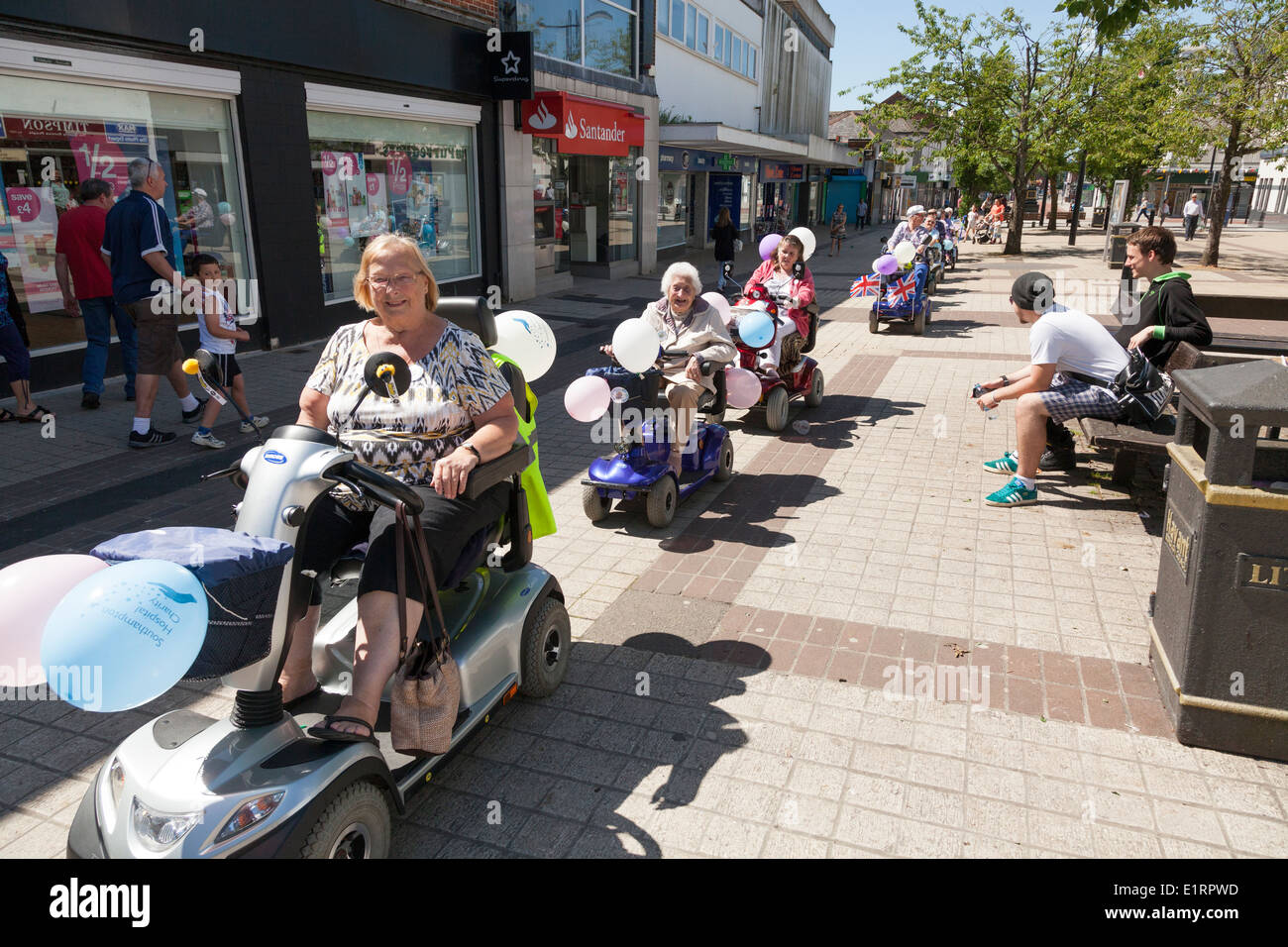 Gruppe von Menschen tun ein Charity-Volkslauf zugunsten von Southampton Krankenhaus auf dekoriert Mobilität Roller. Stockfoto