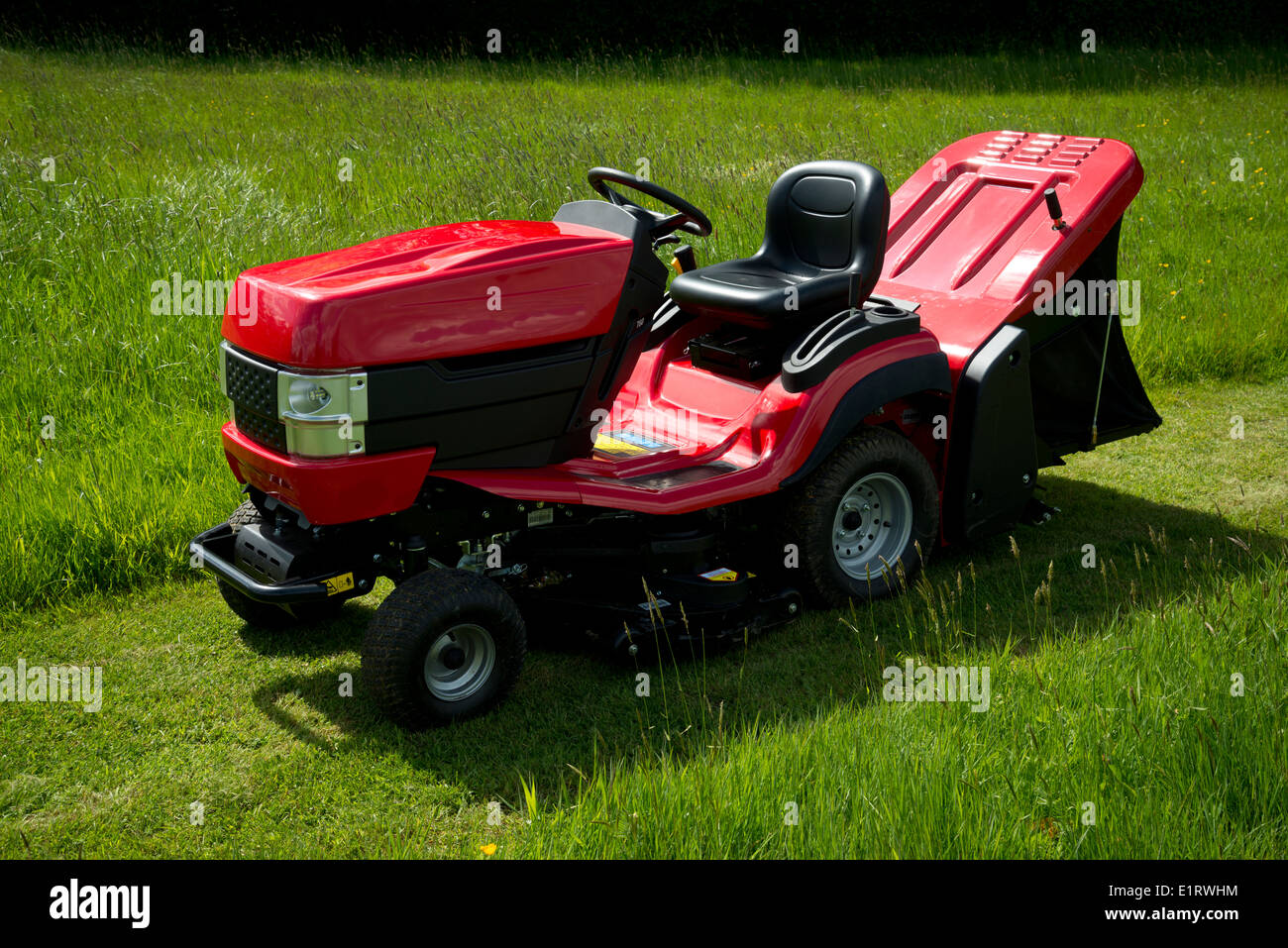 Roter Garten Traktor oder Fahrt auf Mäher, in einem grünen Garten. Stockfoto