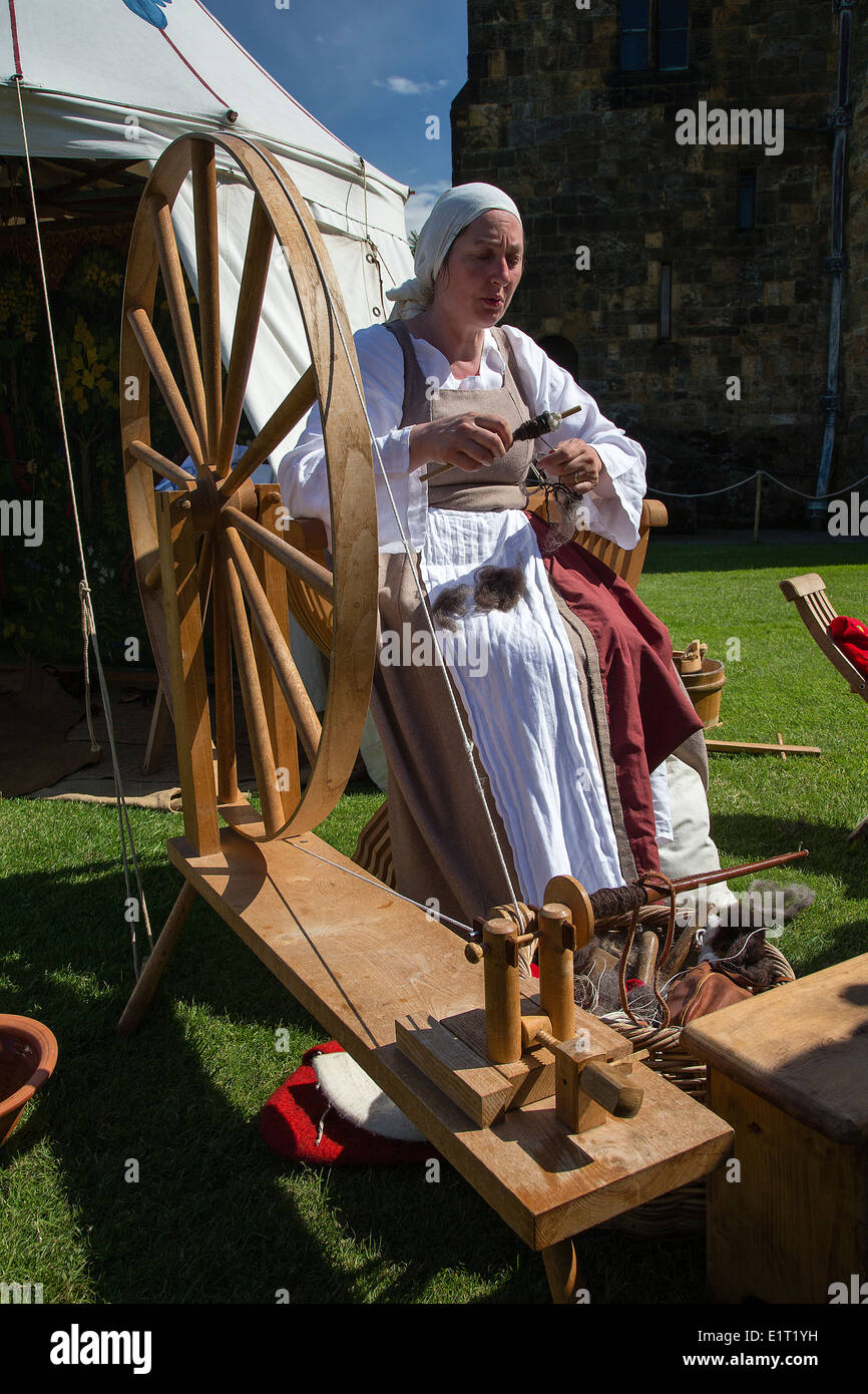 Frau in traditioneller Kleidung Spinnen Wolle auf einem alten Spinnrad bei Alnwick Castle, wo Harry Potter gedreht wurde. Stockfoto