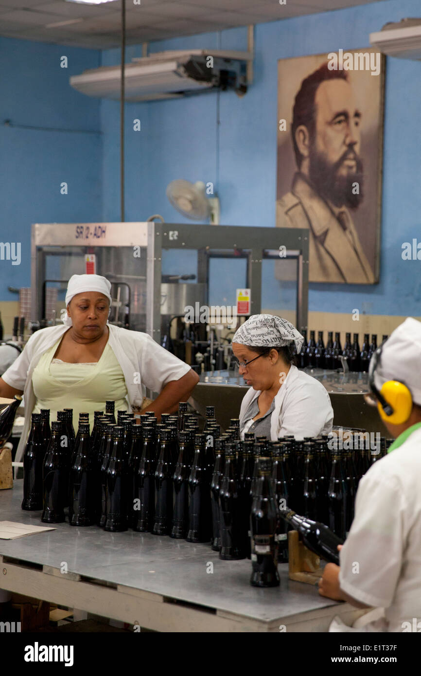 Menschen arbeiten in einer Rumfabrik mit Fidel Castro in Havanna, Kuba im Hintergrund Stockfoto
