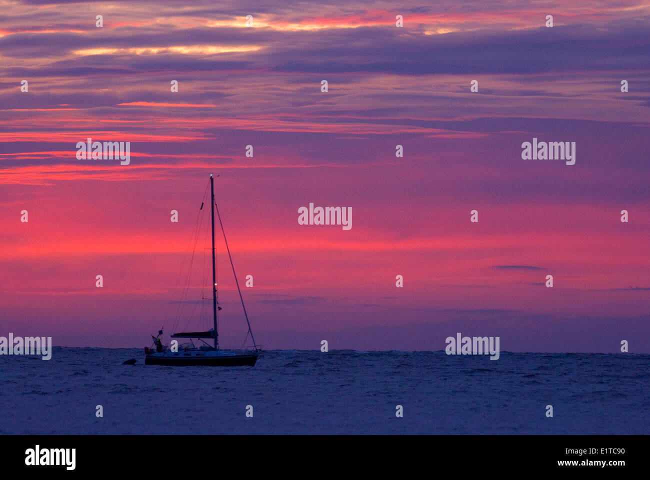 Kajütsegelboot gegen einen lila und rosa Himmel Stockfoto