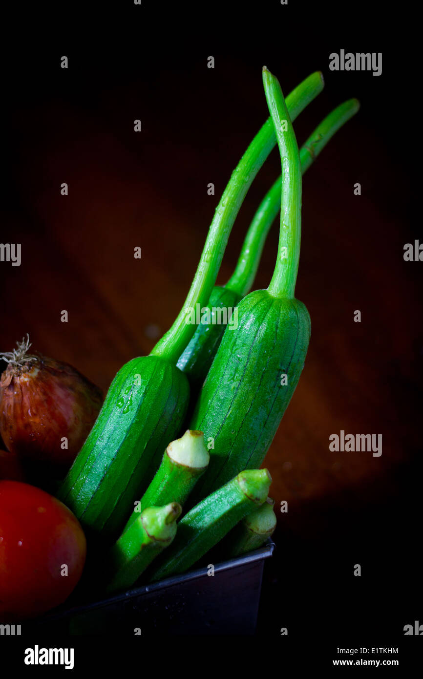Frisches Gemüse [drei Luffa] vier Okra Zwiebel Tomaten zusammen im Feld Container ergeben sich Wurzeln roh grün gelb rot Farbe Stockfoto
