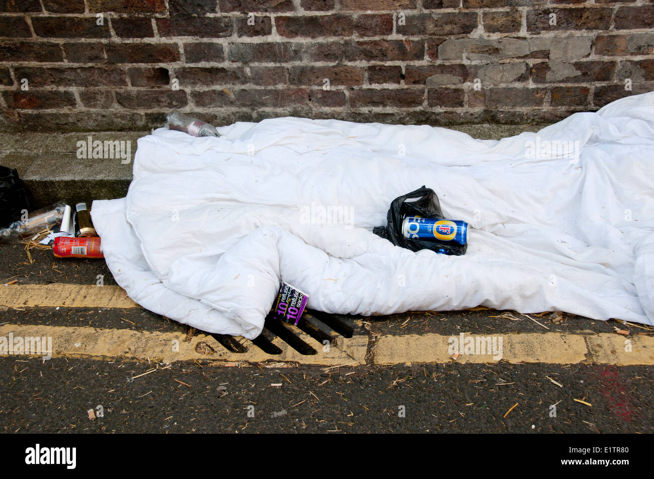Buxton Street an der Brick Lane, East London. 8. Juni 2014. Schlafen in der Gosse. Verlassene Bettdecke und Bier Dosen. Stockfoto