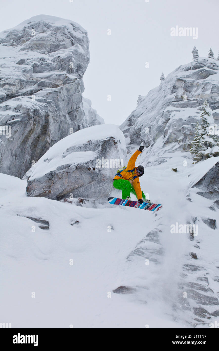 Eine männliche Snowboarder fällt eine Klippe in Revelstoke Mtn Resort, BC Stockfoto