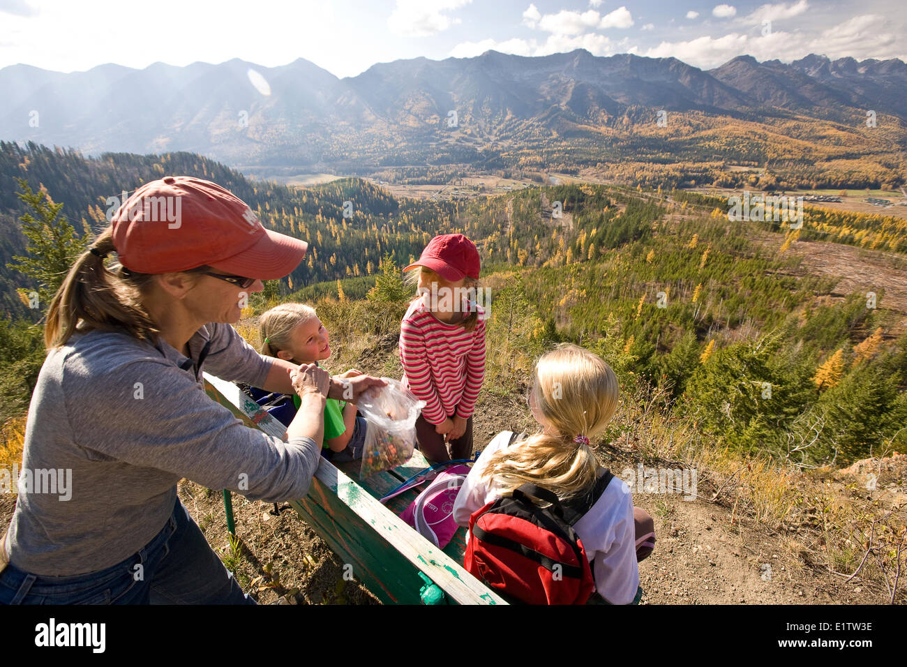 Frau mit Töchtern entspannen Sie auf Bank bei Wanderungen auf Castle Mountain Trail im Herbst, Fernie, BC, Kanada. Stockfoto