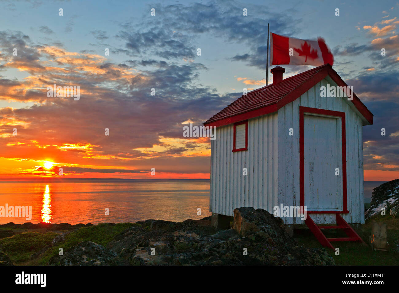 Einen echten kanadischen Plumpsklo bei Sonnenuntergang mit einer kanadischen Flagge auf Quirpon Insel vor der Great Northern Halbinsel gelegen Stockfoto