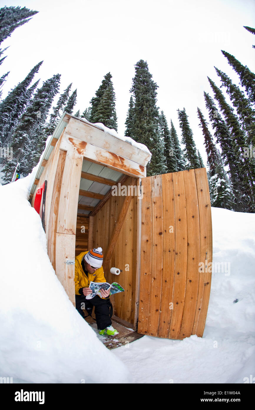 Backcountry Skifahrer liest in einer Zeitschrift während im Nebengebäude, Eisfall Lodge, Canadian Rockies, Golden, BC Stockfoto