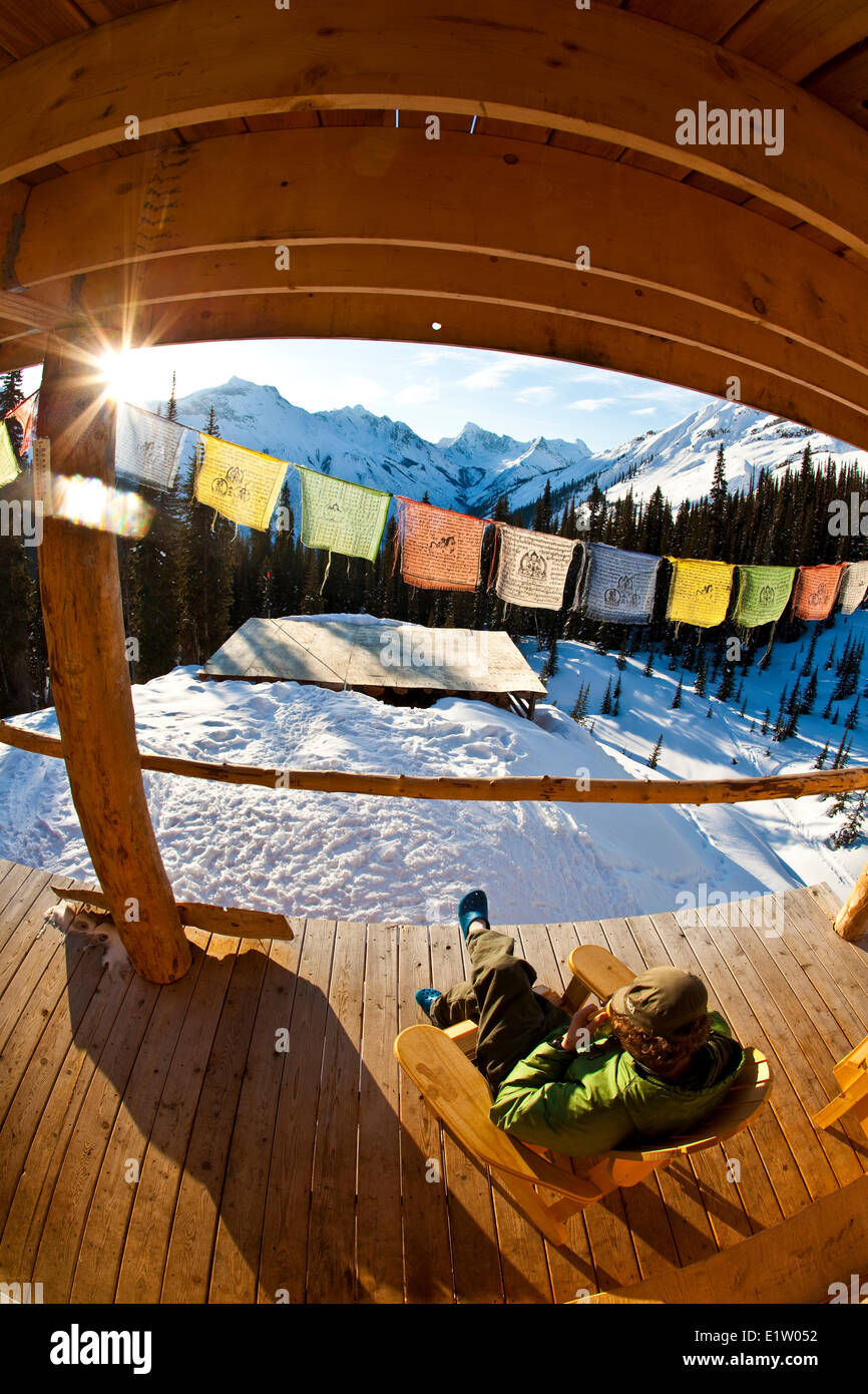 Ein Mann genießen Sie Sonnenaufgang und einen Kaffee im Backcountry-Ski-Hütte. Eisfall Lodge, Golden, BC Stockfoto