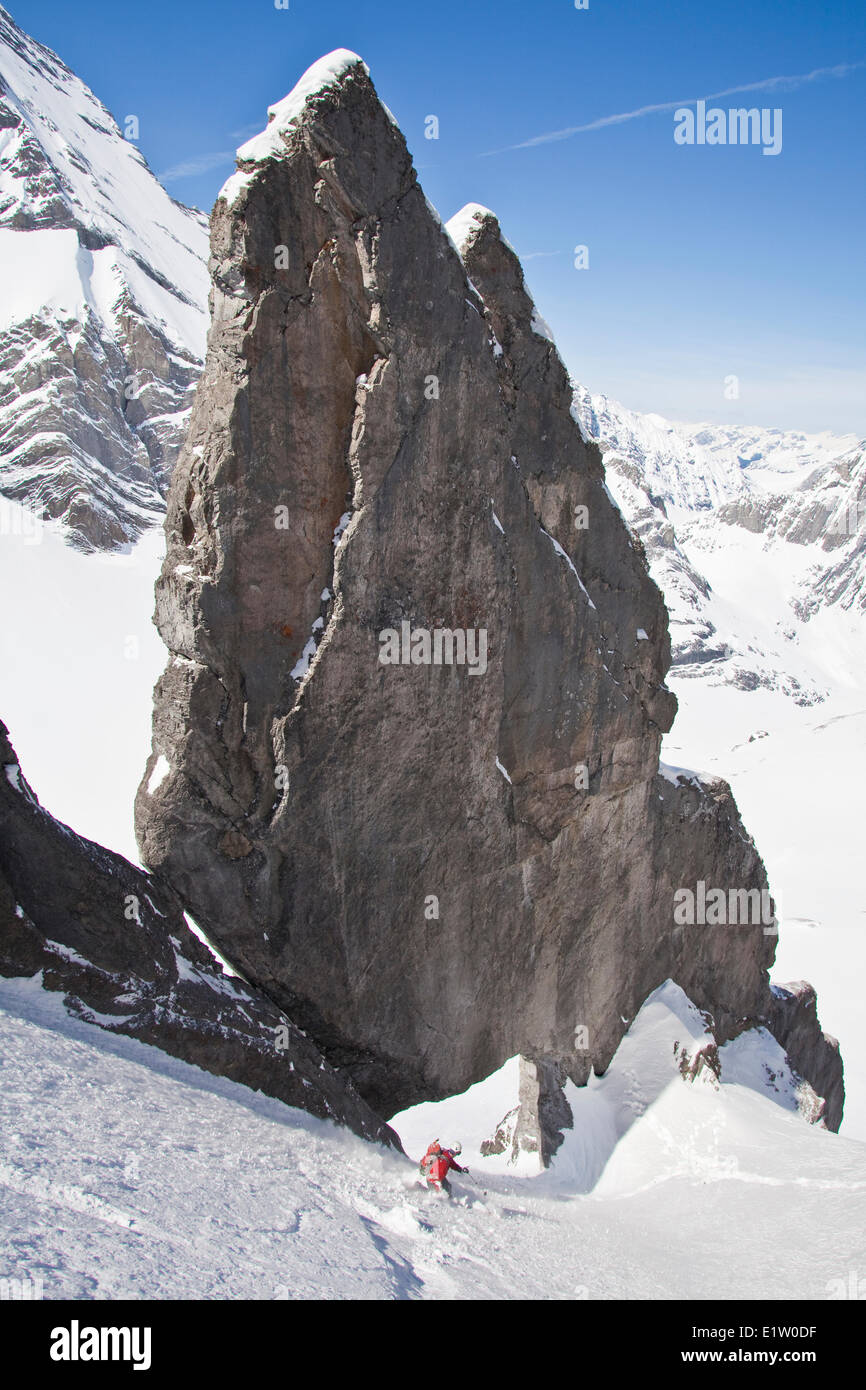 Ein männlicher Backcountry Skifahrer auf Tele Ski Tropfen in einem steilen Couloir mit einem einzigartigen Kalkstein Bogen drin. Mt. Französisch Peter Lougheed Stockfoto