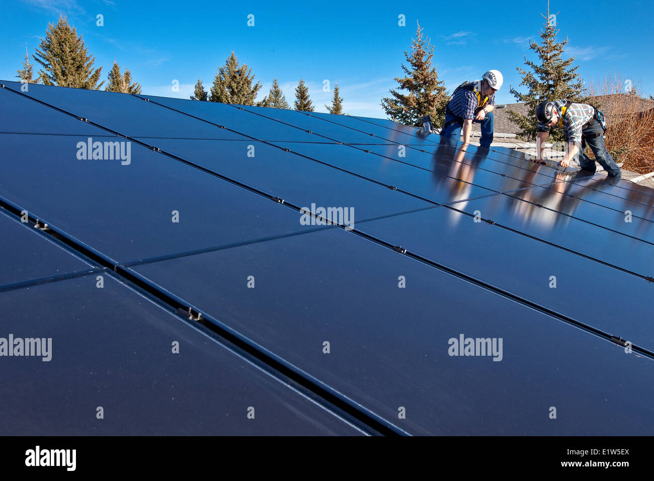 Zwei Solar-Panel-Installationsprogramme installieren Sonnenkollektoren auf Dach, Alberta Ausläufer in der Nähe von Black Diamond, Alberta, Kanada. Stockfoto