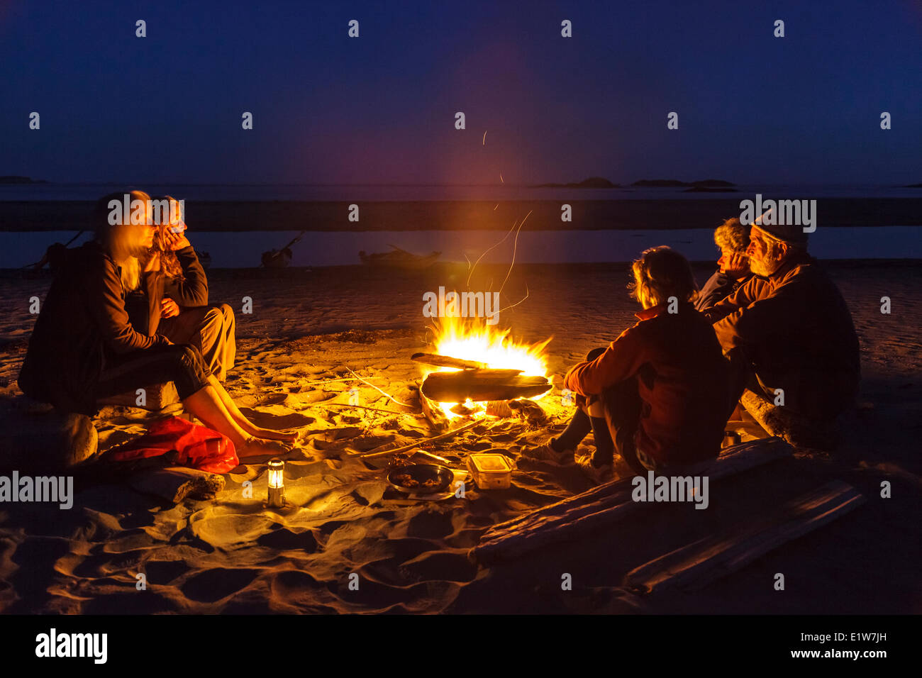 Fünf Kajakfahrer entspannen um ein Lagerfeuer auf Vargas Insel nach einem Tage Paddel im Clayoquot Sound, Britisch-Kolumbien, Canada.Model Re Stockfoto