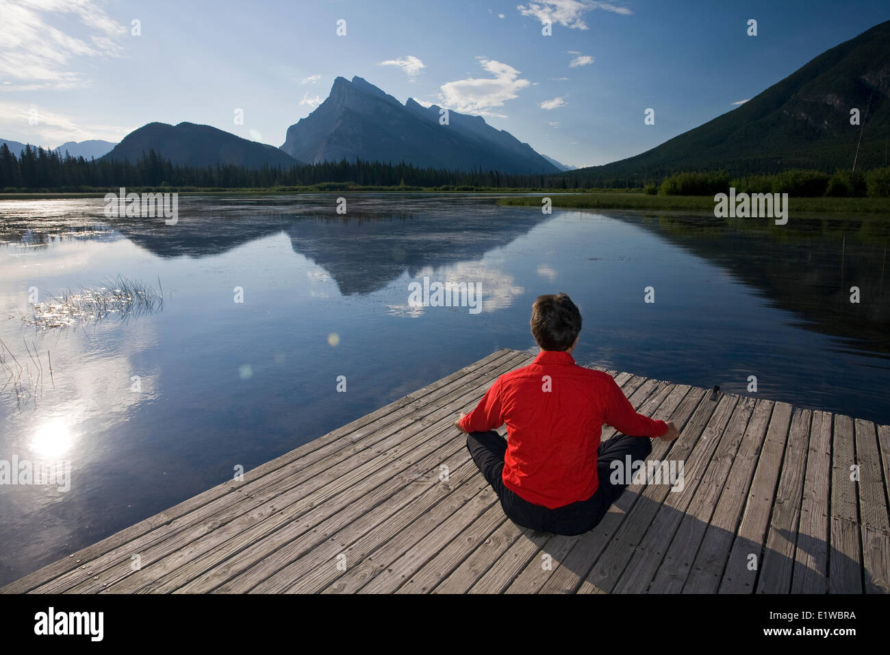 54 Jahre alt, Männlich meditieren auf Dock am Vermillion Lake, Banff, Alberta, Kanada Stockfoto