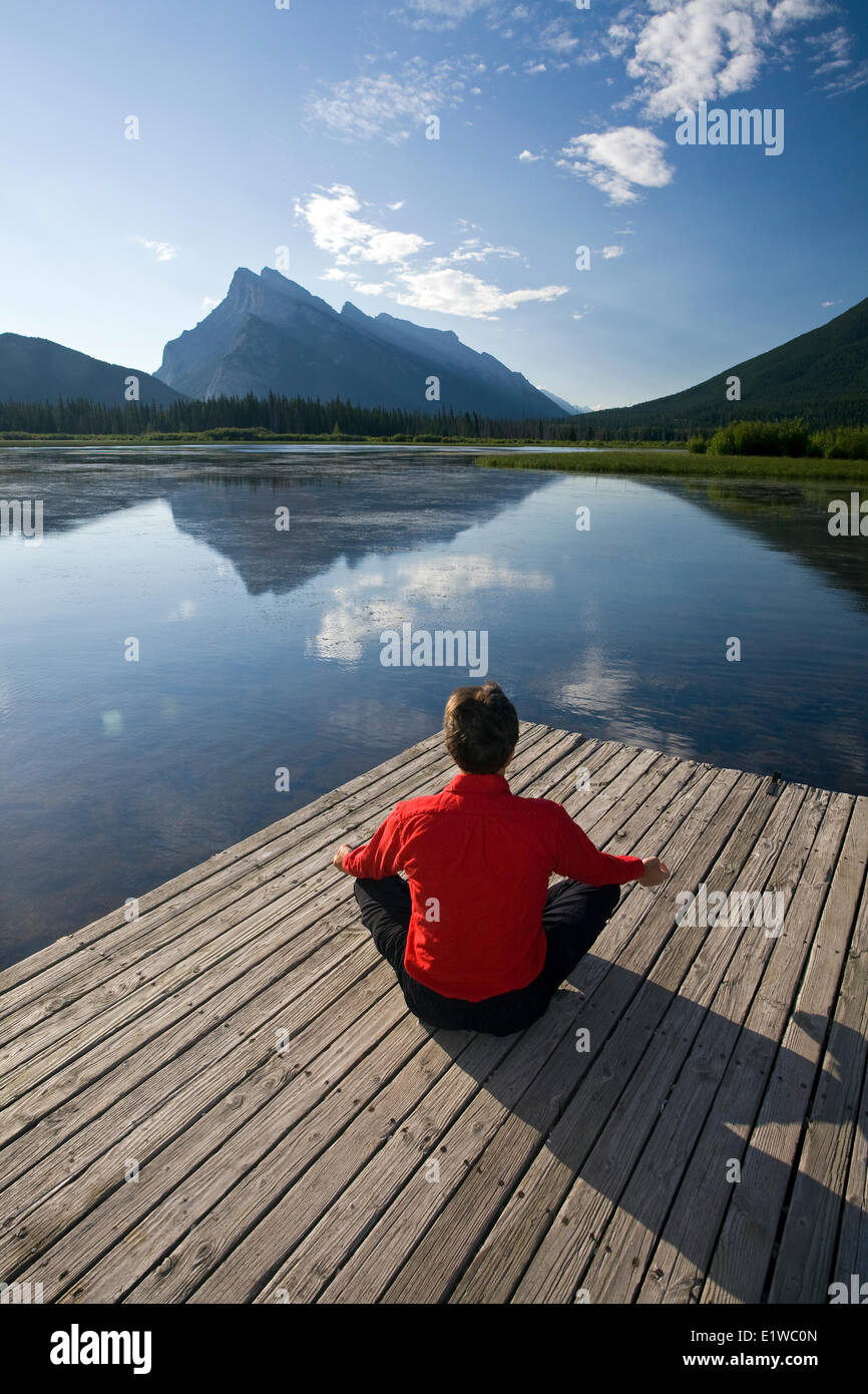 54 Jahre alt, Männlich meditieren auf Dock am Vermillion Lake, Banff, Alberta, Kanada. Stockfoto