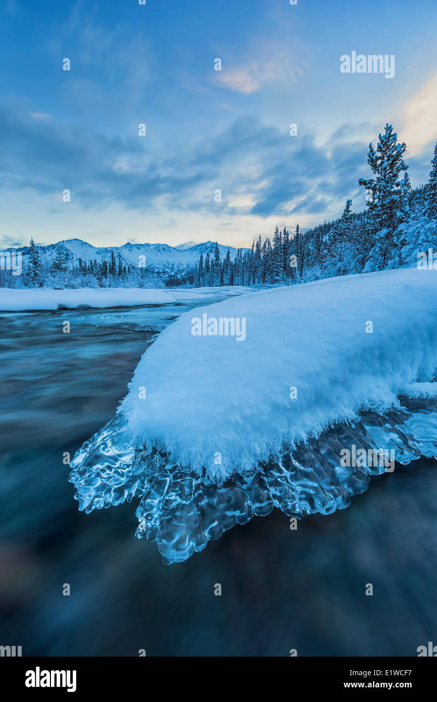 Morgendämmerung über ein ein Eis bedeckt Rock befindet sich in den Wheaton River in der Nähe von Whitehorse, Yukon. Stockfoto