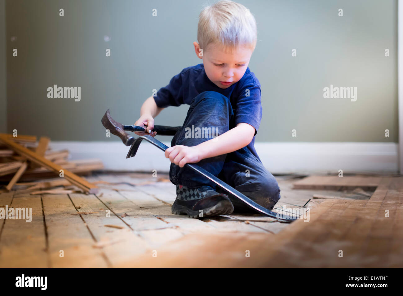 kleiner Junge Tischler mit einem Hammer und Hartholz Boden zu spielen. Stockfoto