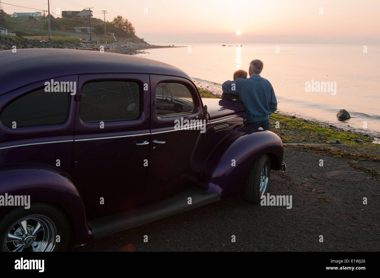 Ein älteres Ehepaar beobachten Sie den Sonnenaufgang am Punkt Holmes Beach von ihren 1939 Ford. Courtenay, BC Stockfoto