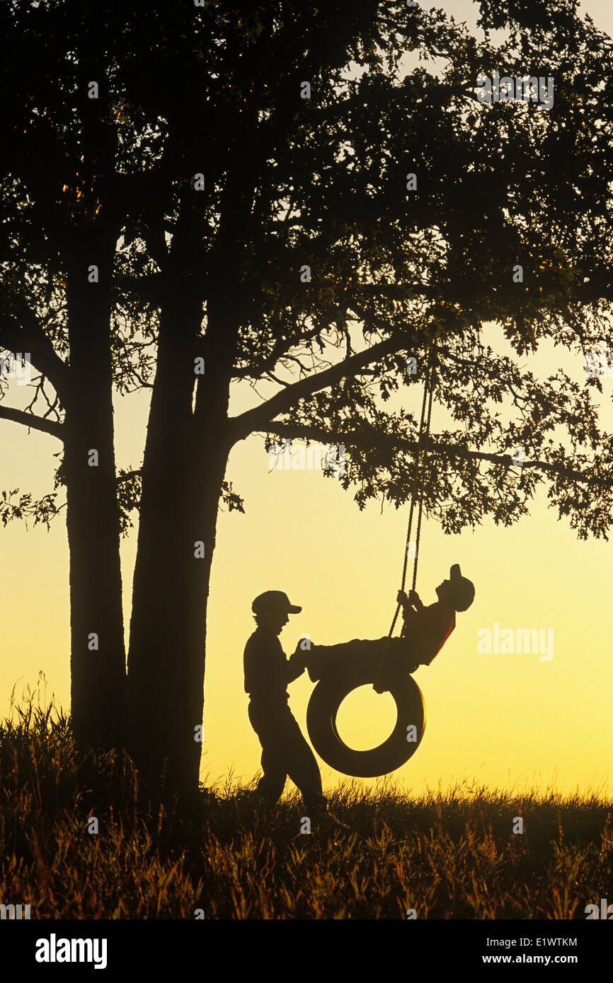 Jungs spielen auf Reifen Schaukel unter Eiche, Vögel Hill Provincial Park, Manitoba, Kanada Stockfoto