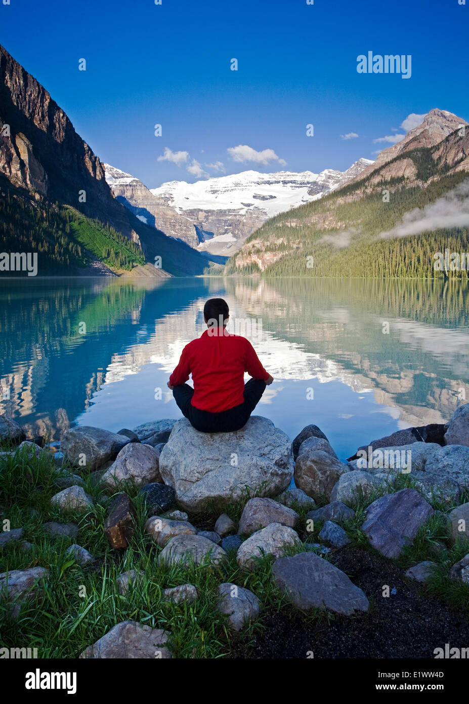 Mittleren Alters, Männlich meditieren auf Felsen am Lake Louise, Alberta, Kanada. Stockfoto