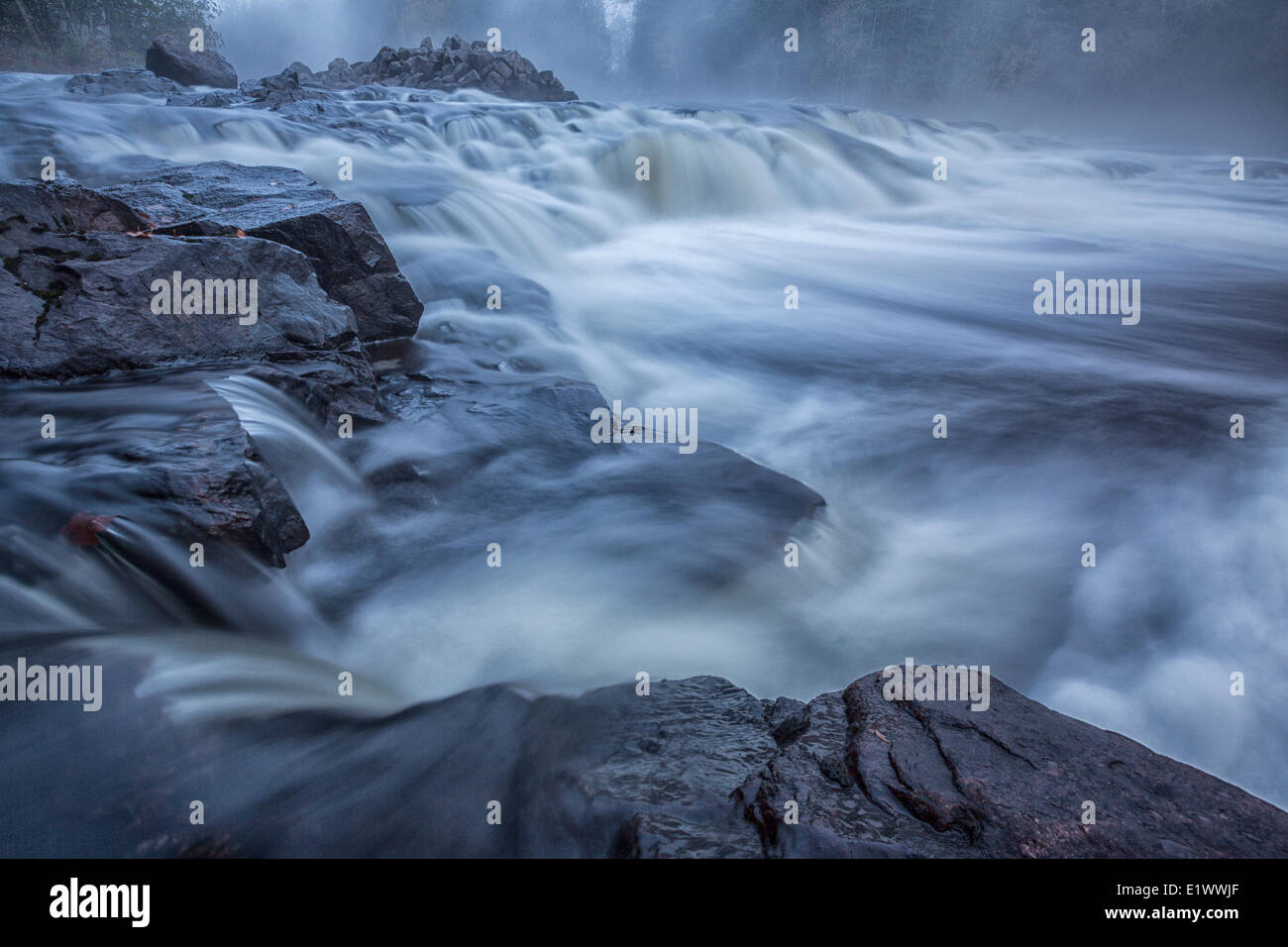 Nebel steigt aus der Petawawa River, wie es über einige Felsen bilden eine kleine Waterall auf der Ost Seite Algonquin Park Ontario fließt. Stockfoto