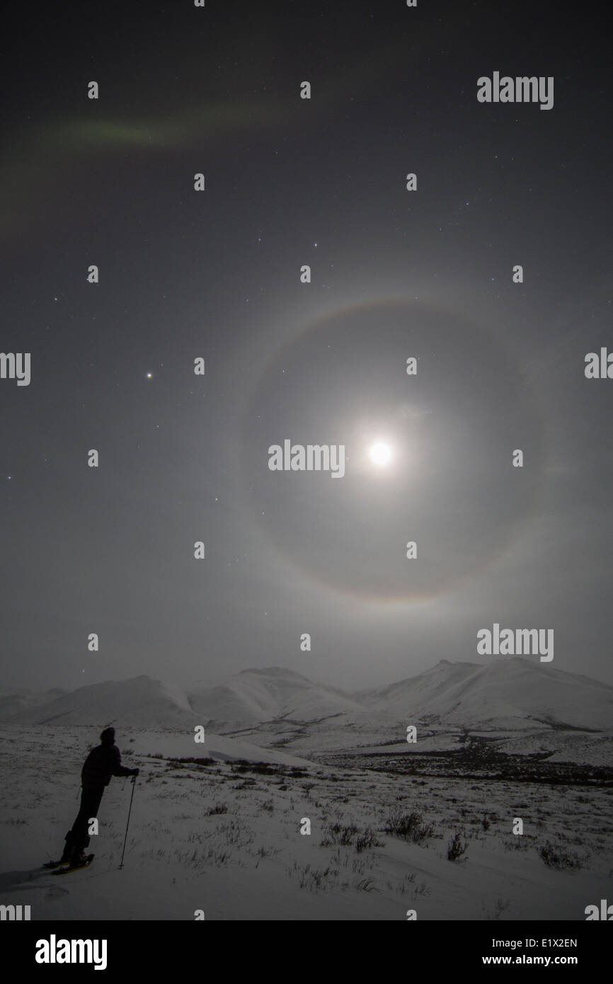 Halo um den Mond herum, wie eine Person beim Schneeschuhwandern auf dem Dempster Highway, Yukon Uhren. Stockfoto