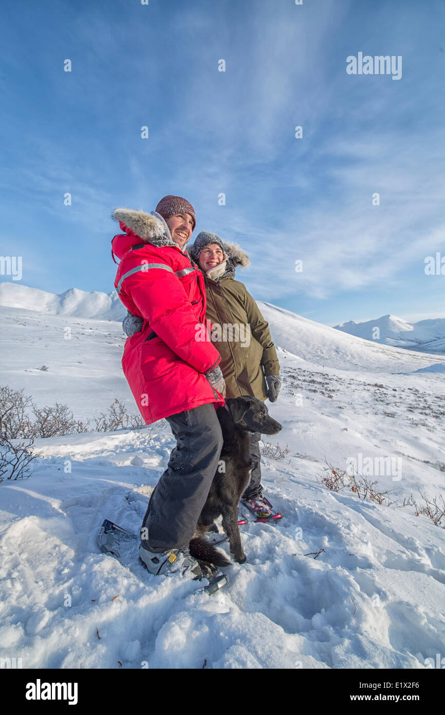 Brautpaar stehend mit ihrem Hund auf einem Hügel entlang der DempsterHighway, Yukon nach Schneeschuhwandern an der Spitze. Stockfoto