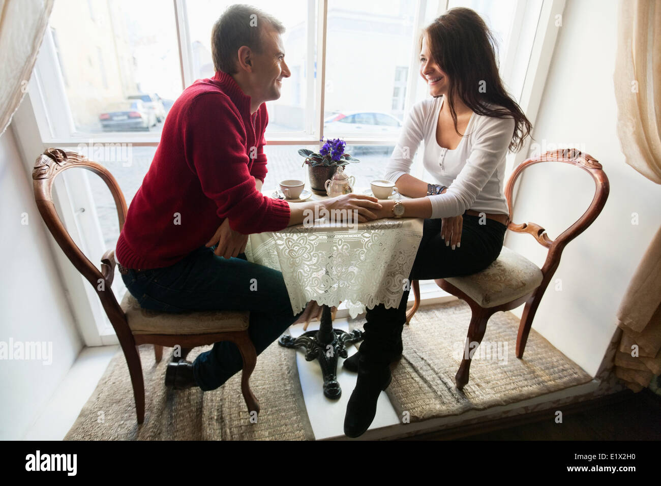 Volle Länge des jungen Liebespaar Händchenhalten und sahen einander im café Stockfoto