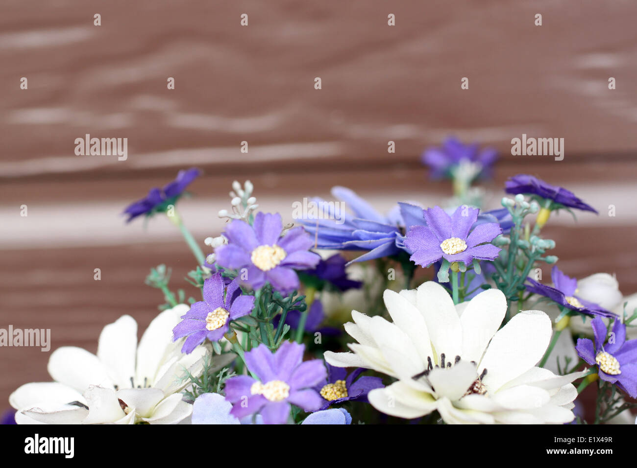 violette und weiße Farbe der künstlichen Blumenstrauß auf braunem Hintergrund. Stockfoto