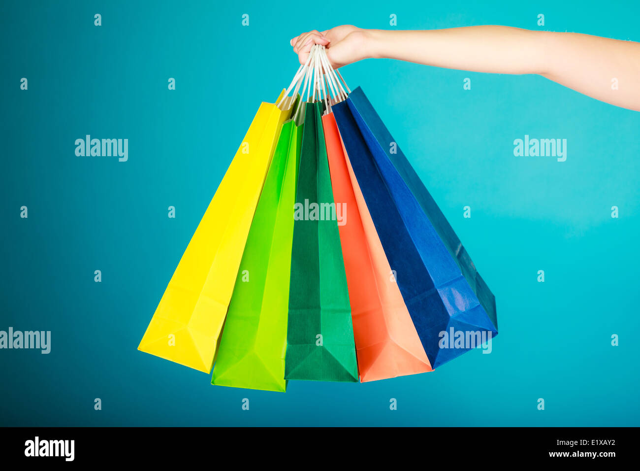 Nahaufnahme der bunten Papier-Einkaufstüten in weiblicher Hand auf lebendige blau. Woman Mädchen Kleider kaufen. Verkauf und Einzelhandel. Stockfoto