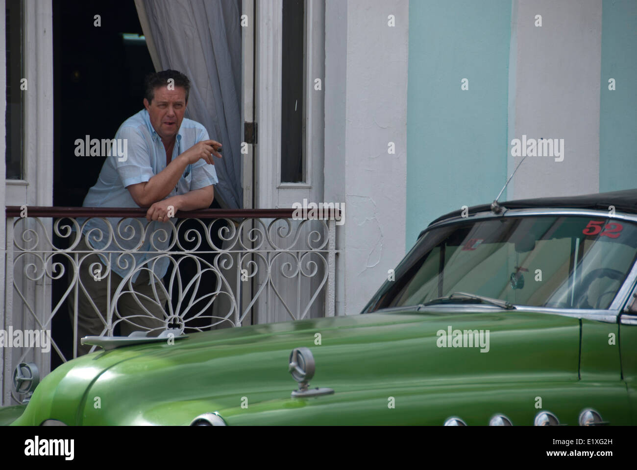 Kubaner raucht eine Zigarre in der Nähe eines amerikanischen Oldtimers in Cienfuegos, Kuba Stockfoto