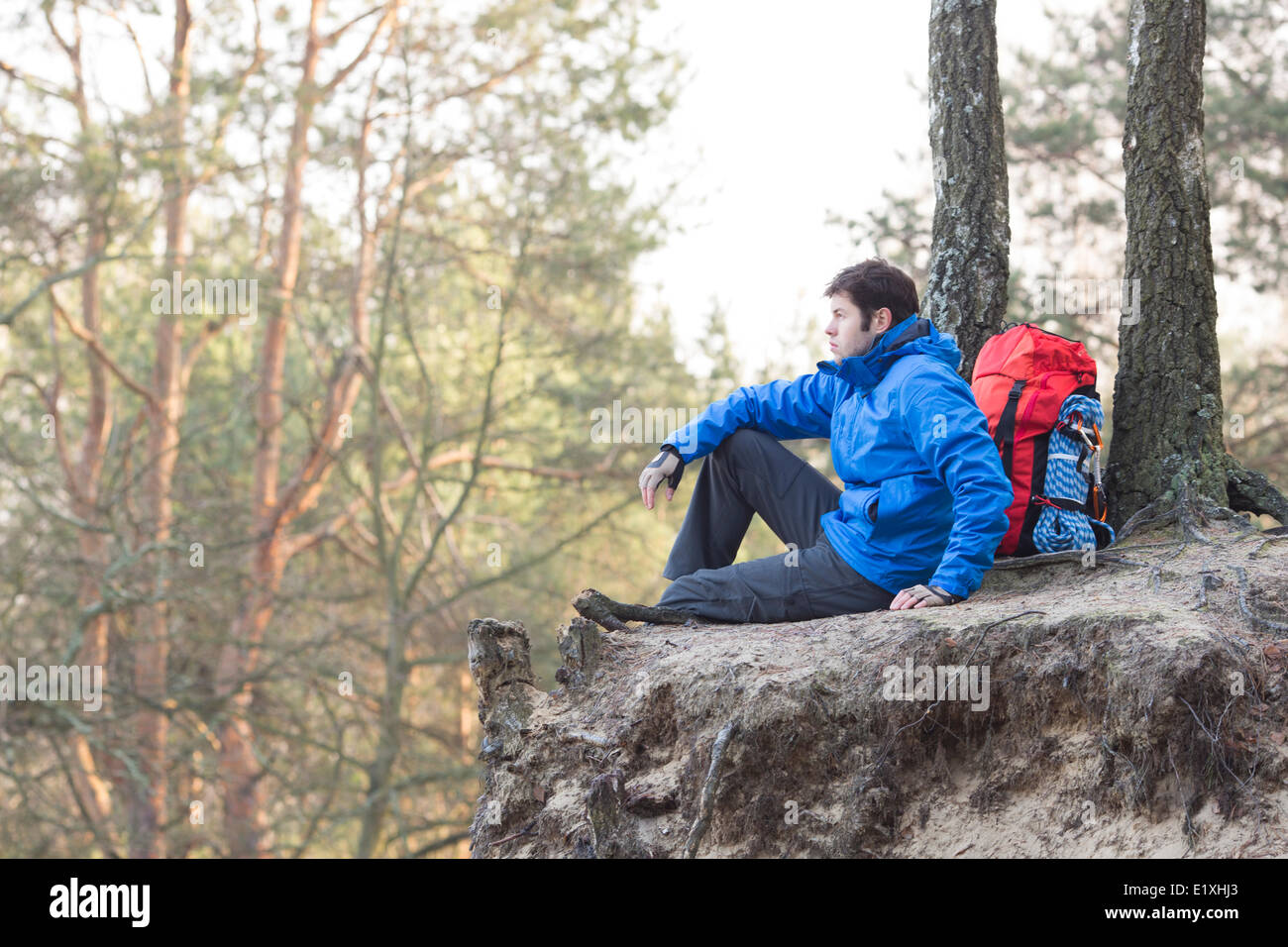 Seitenansicht der Wanderer sitzen am Rand der Klippe im Wald Stockfoto
