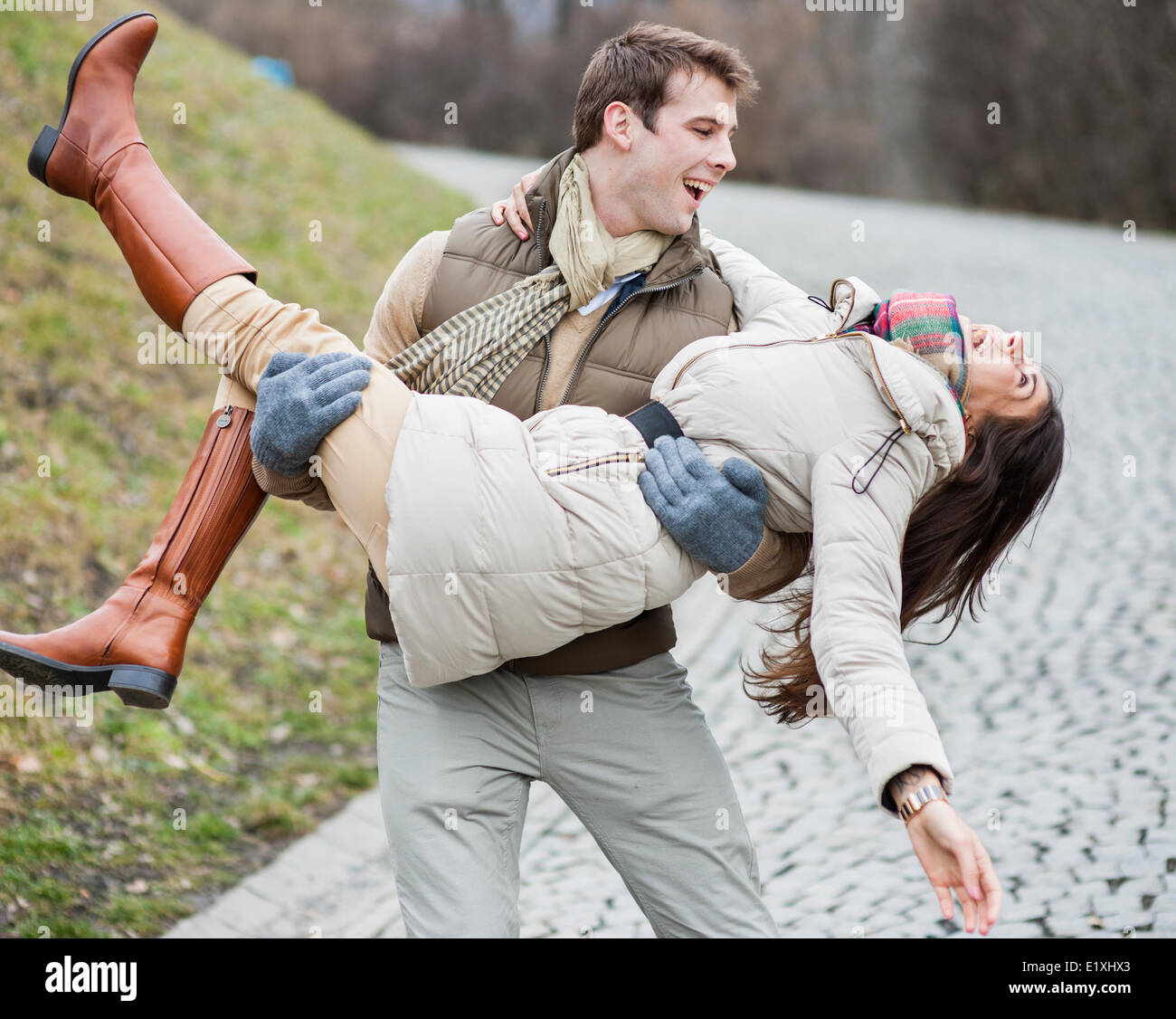 Glücklicher Mann trägt Frau im park Stockfoto