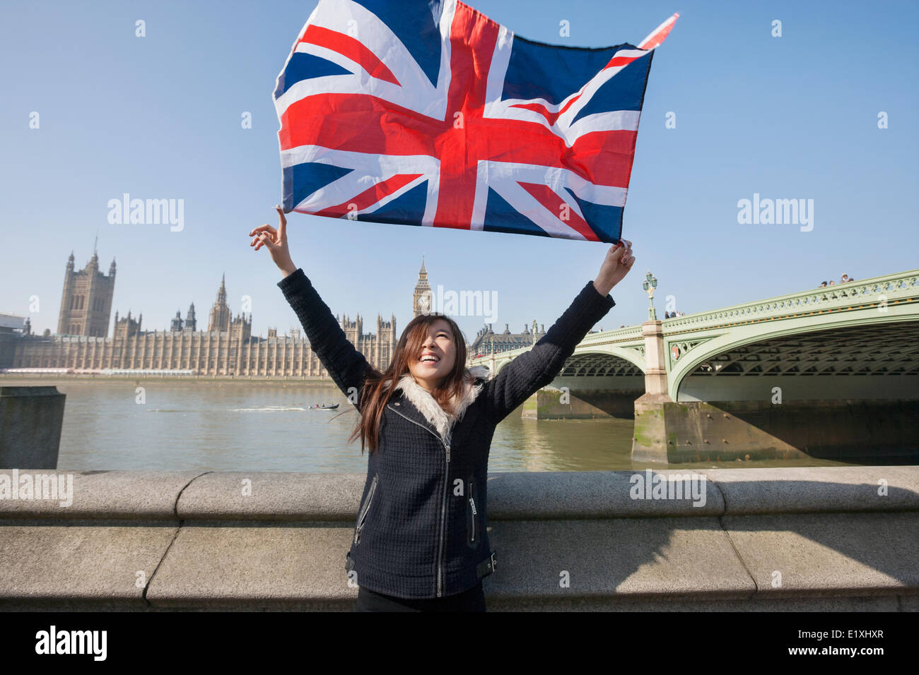 Glückliche Frau mit britischer Flagge stehend gegen Big Ben in London, England, UK Stockfoto