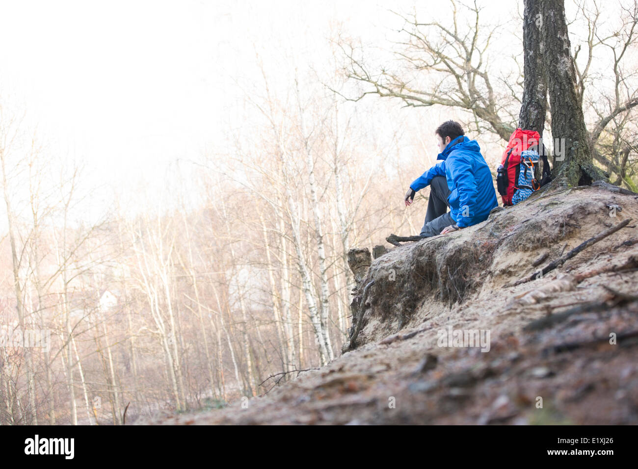 Seitenansicht des männlichen Wanderer sitzen am Rand der Klippe im Wald Stockfoto