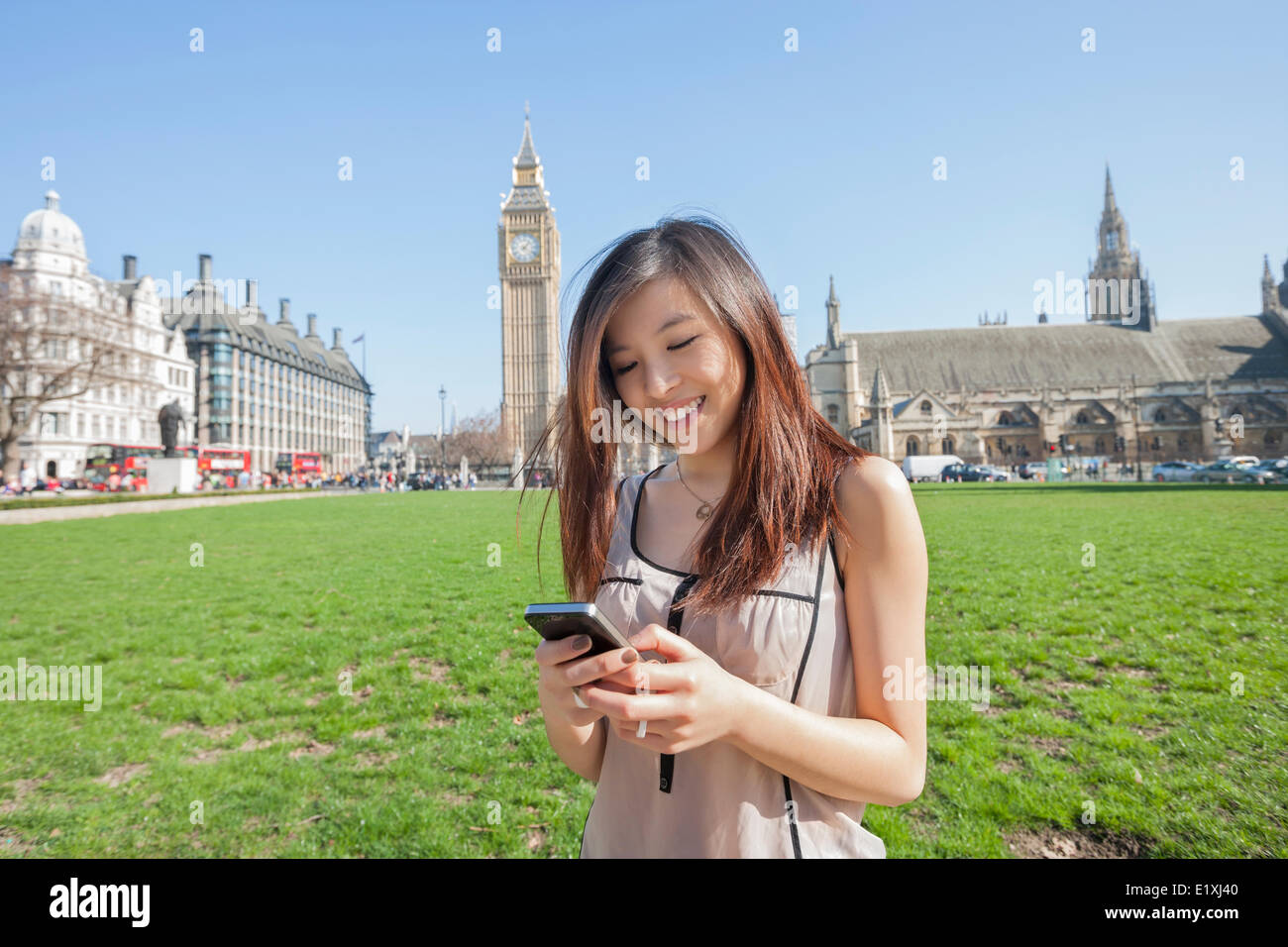 Junge Frau von SMS-Nachrichten über Smartphone gegen Big Ben in London, England, UK Stockfoto