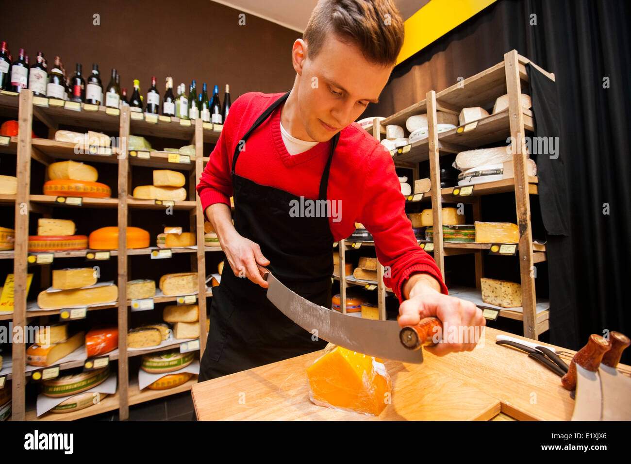 Männliche Verkäufer schneiden Käse drin Stockfoto